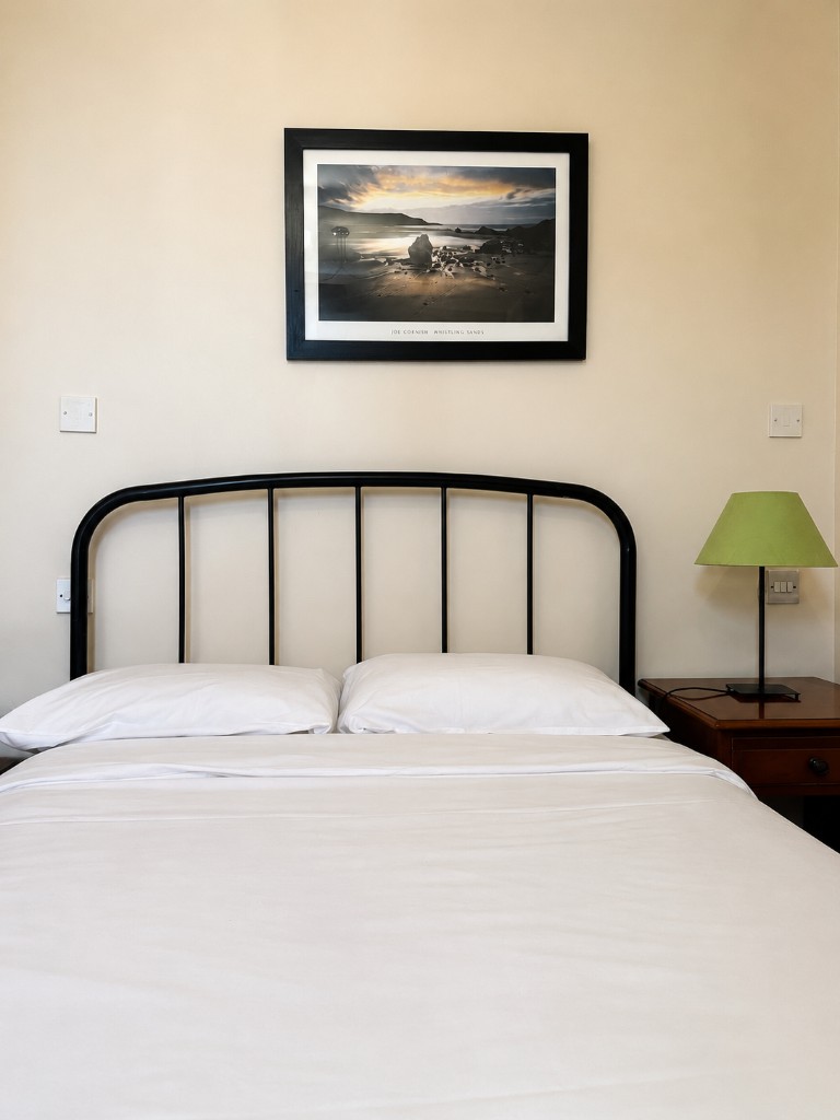 Double room with white linens and metal headboard